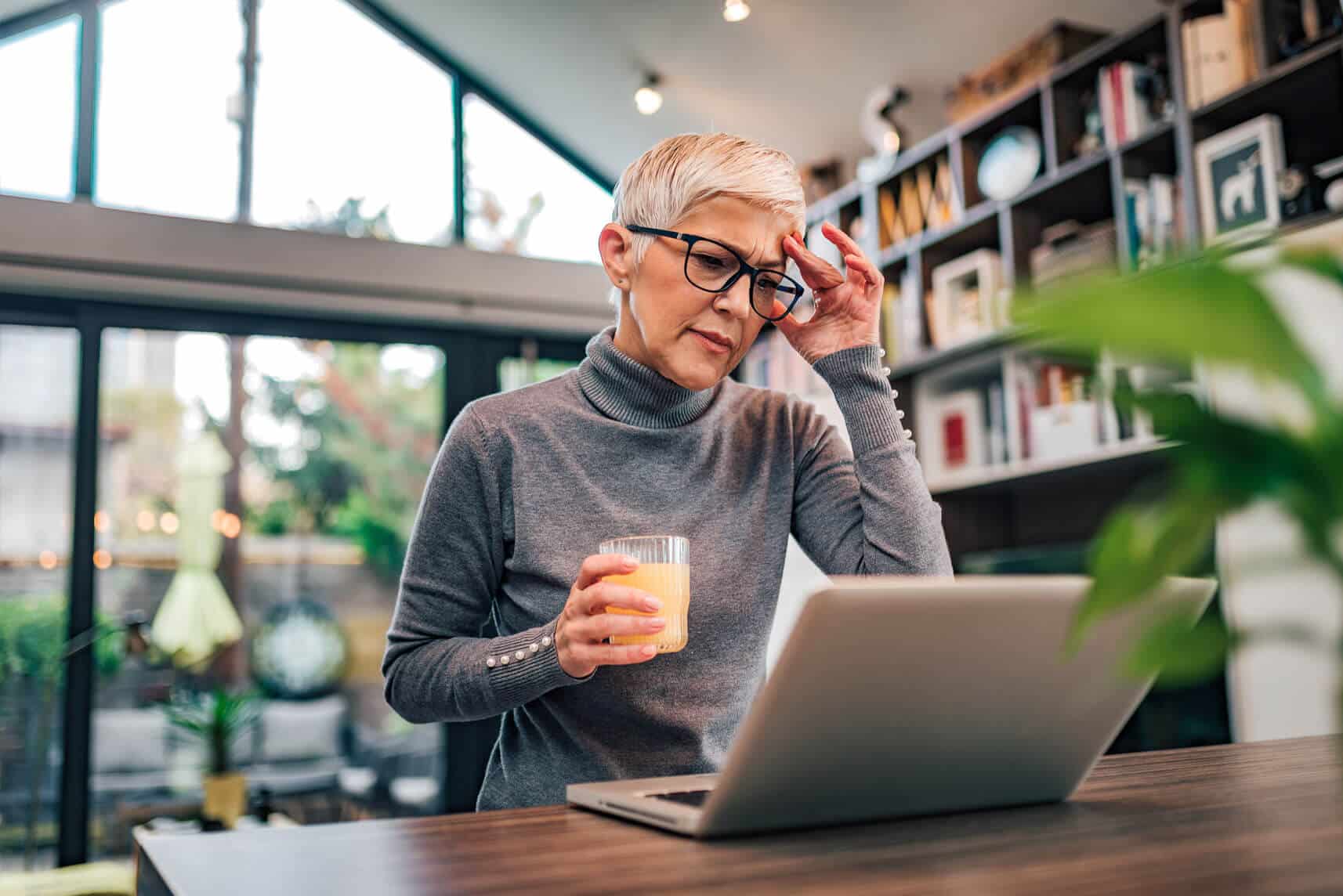 Frau mit Kopfschmerzen am Notebook